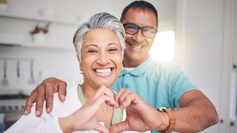 A picture of a man and a lady smiling showing a love heart sign in Apex NC