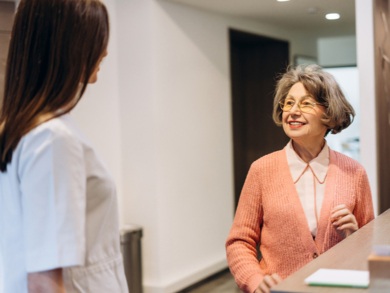 Patient speaking with staff at a dental reception desk