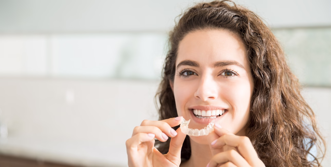 Woman holding an Invisalign clear aligner