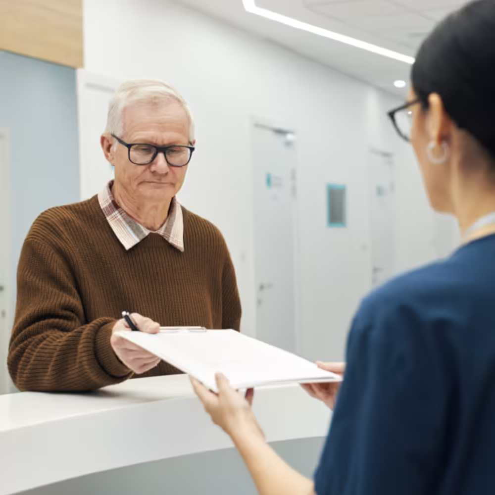 Older patient speaking with dental office staff